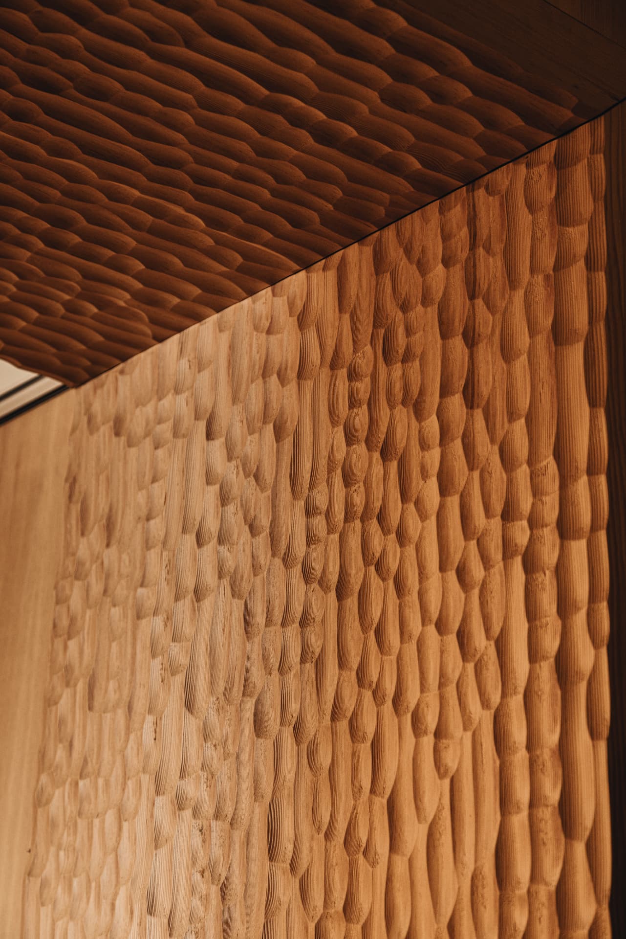 Hand-carved rippled timber surface in raking light