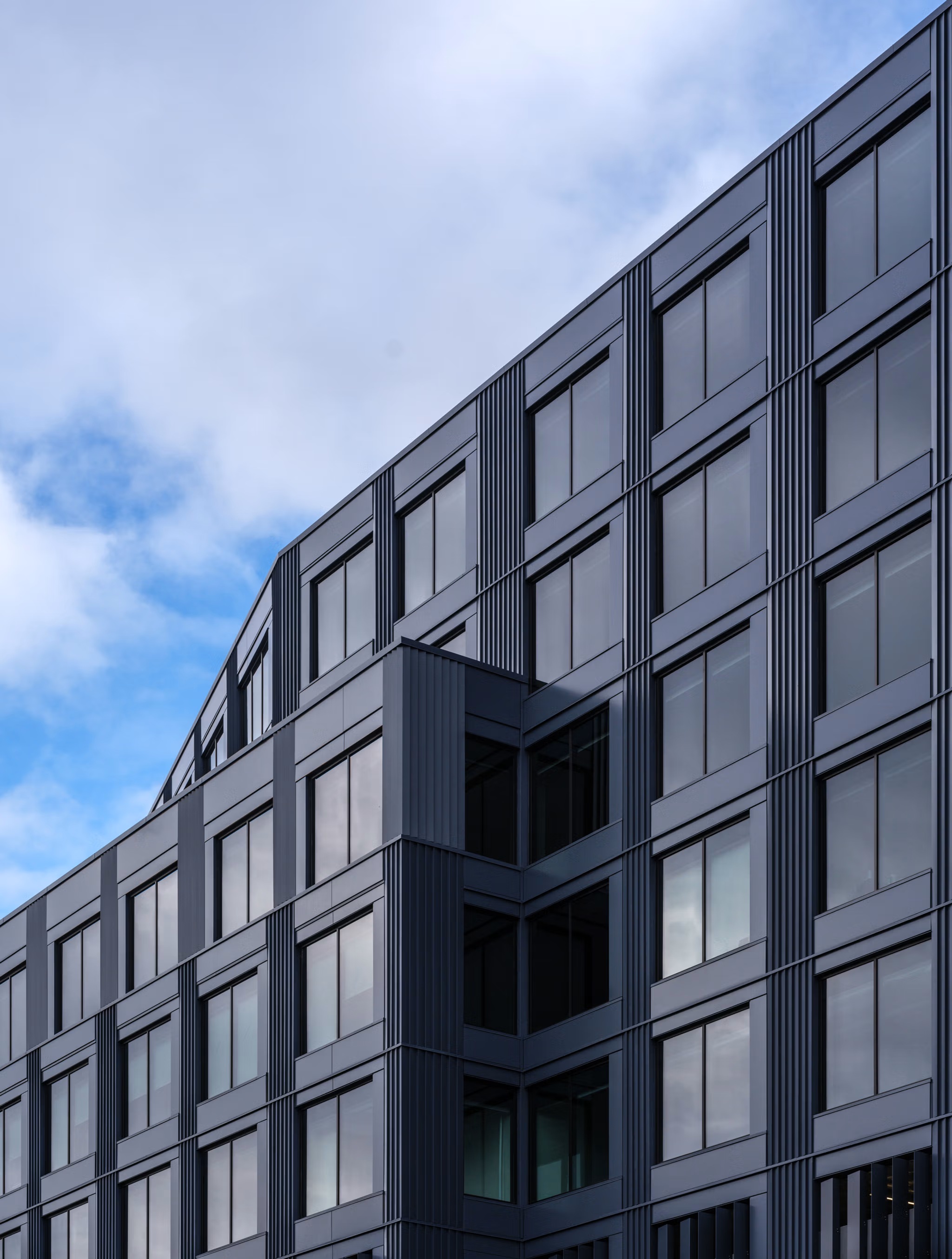 Close view of the Terminal 1 ribbed metal facade turning a corner against a blue sky