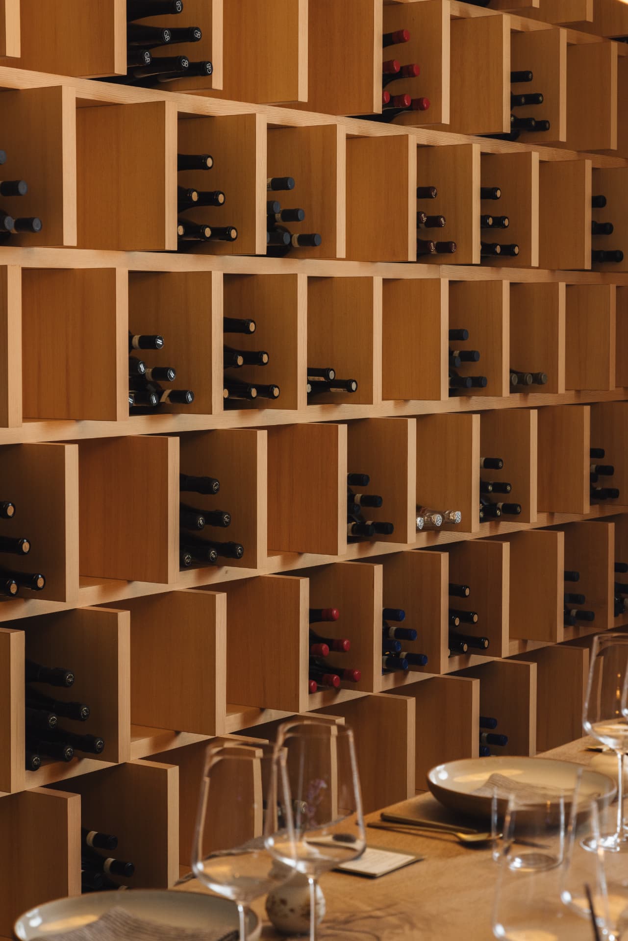 Wine-cube wall with glasses on the table in the foreground