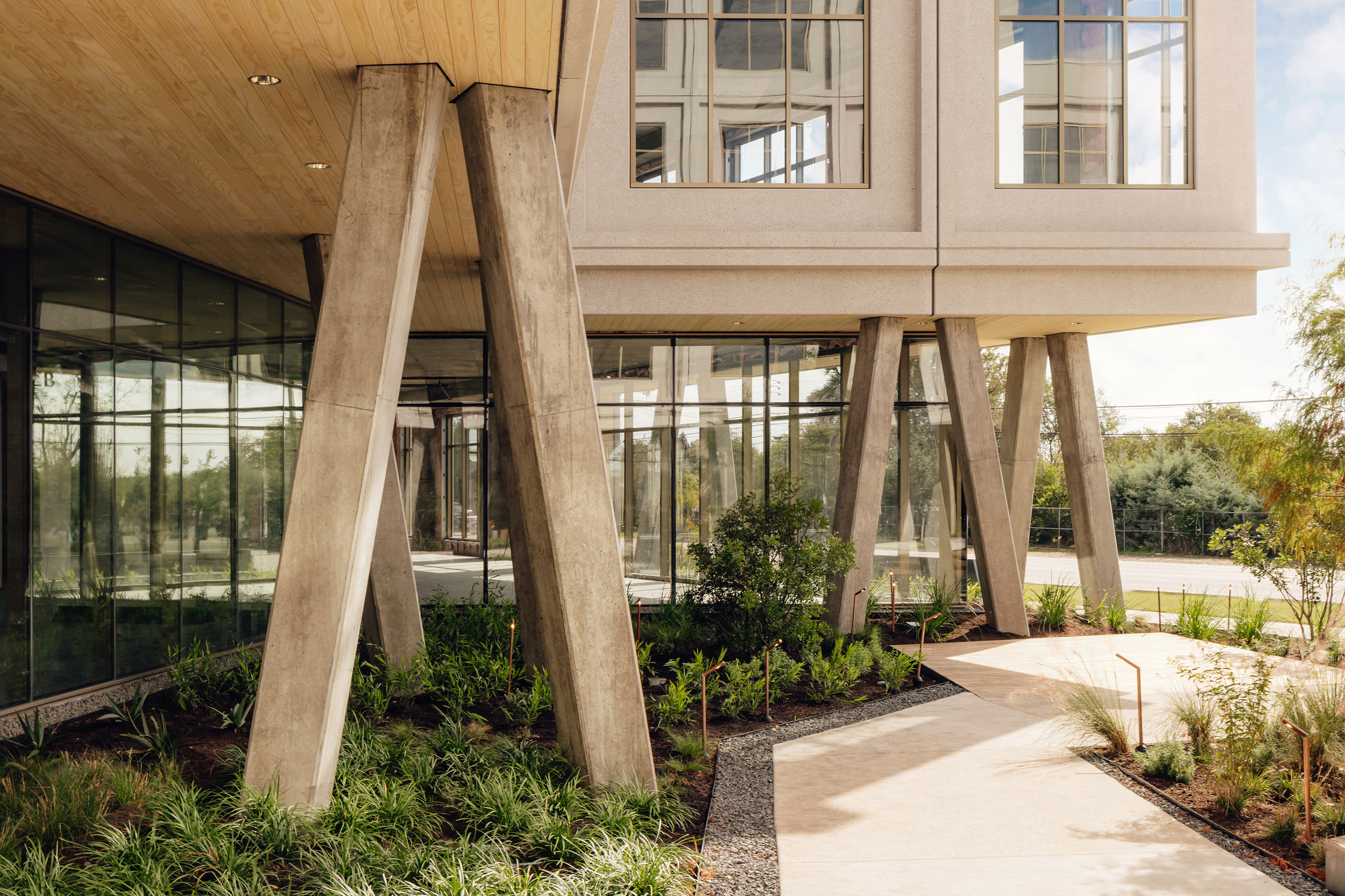 Oblique view beneath the building through angled concrete columns and planting