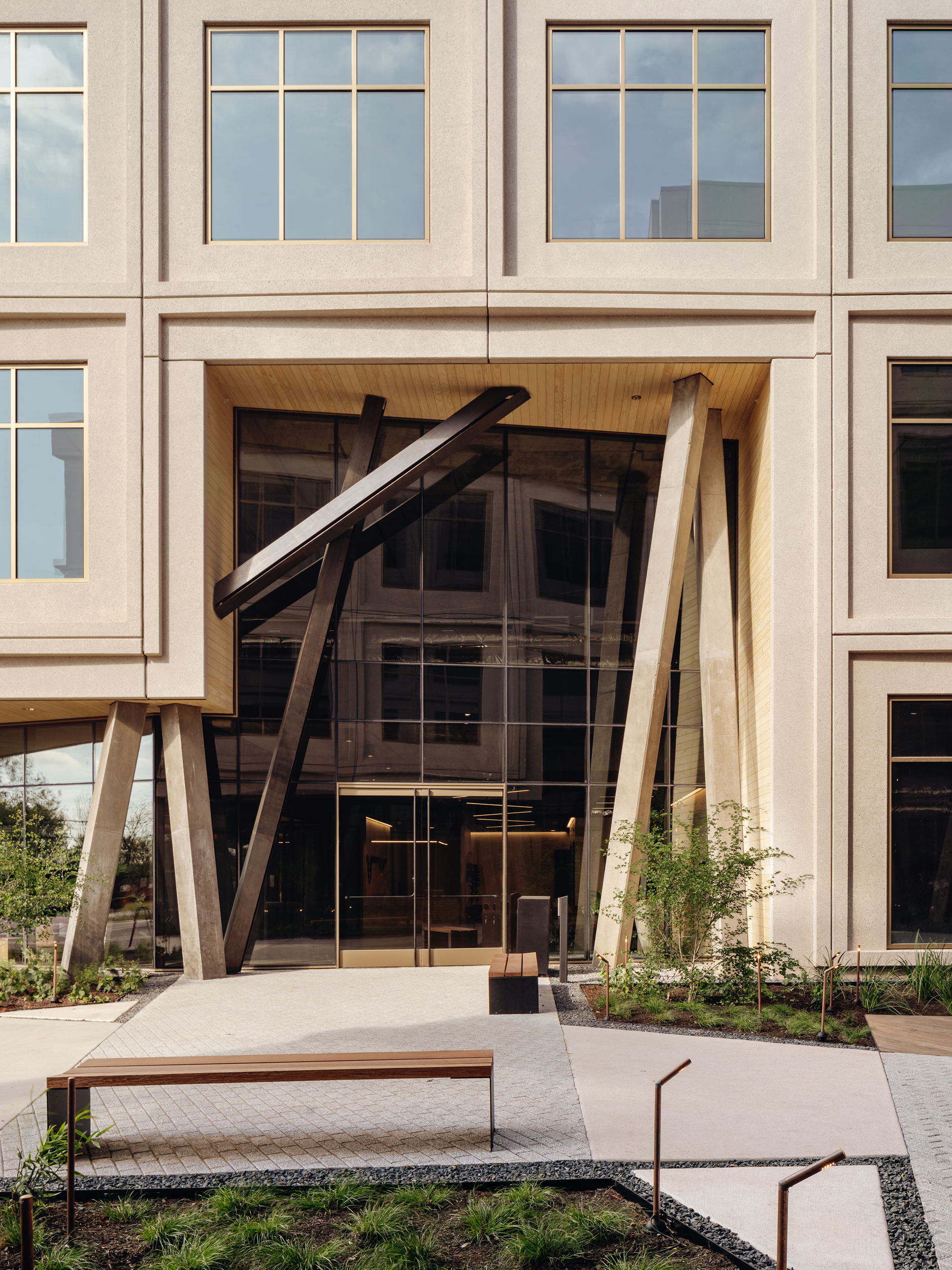 Dark steel portal and bench set into the pale framed courtyard elevation