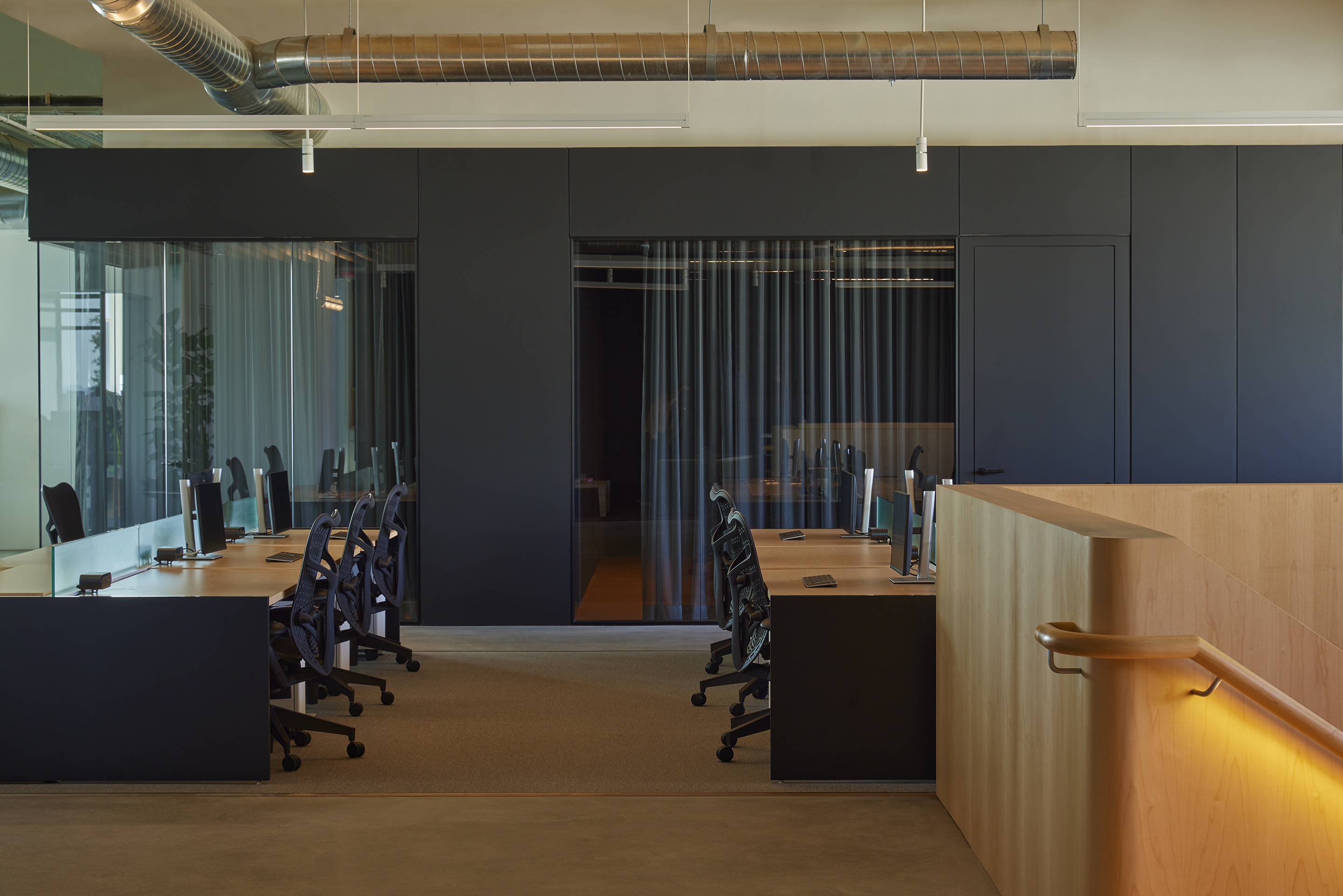 Open workplace floor with desks, dark joinery and a maple balustrade