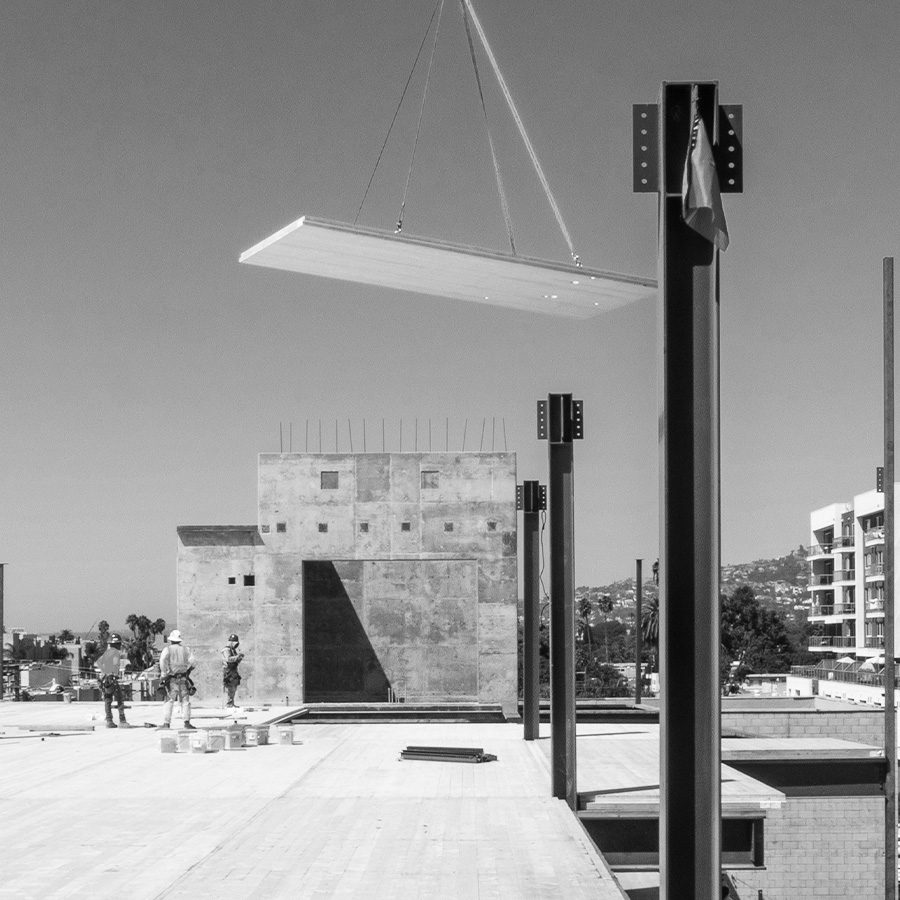 Timber panel suspended from a crane above the steel frame and concrete core