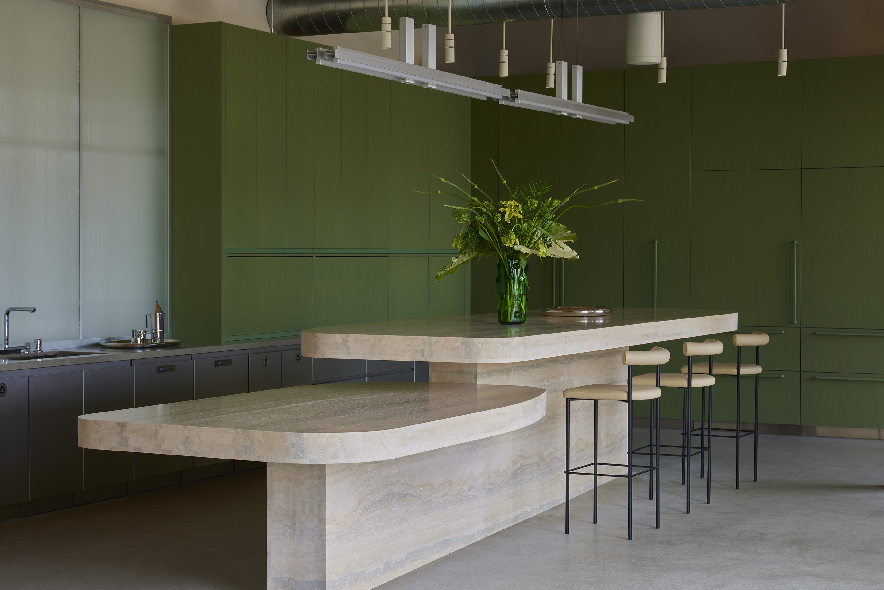 Travertine island and stools against a deep green joinery wall