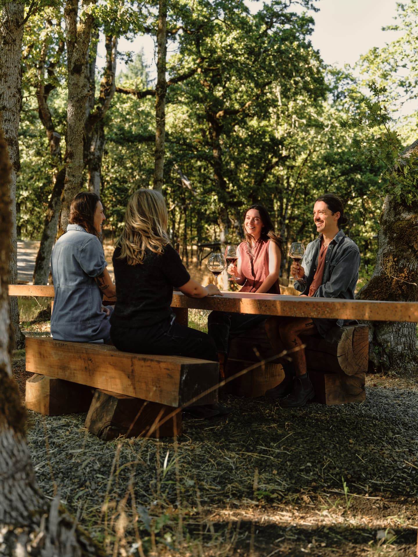 Four people seated on timber benches tasting wine at the terrazzo table