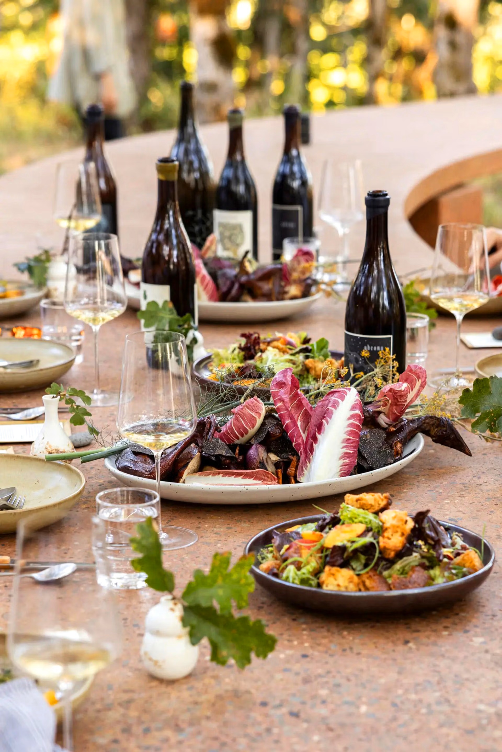Shared meal with wine, seasonal dishes and flowers spread along the terrazzo table