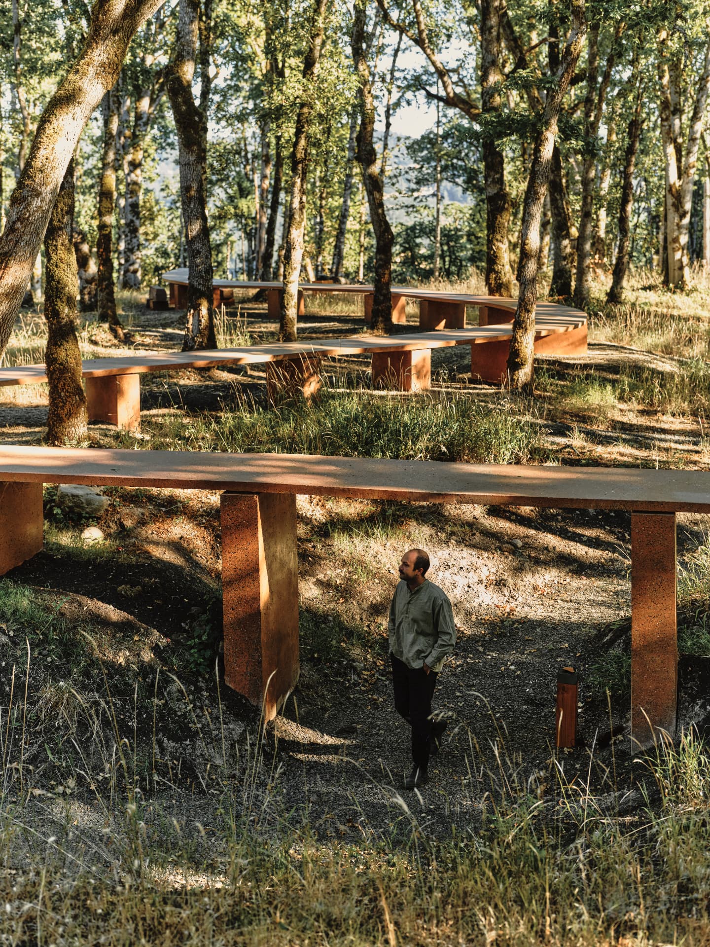 A visitor standing beneath the completed table where it bridges a swale