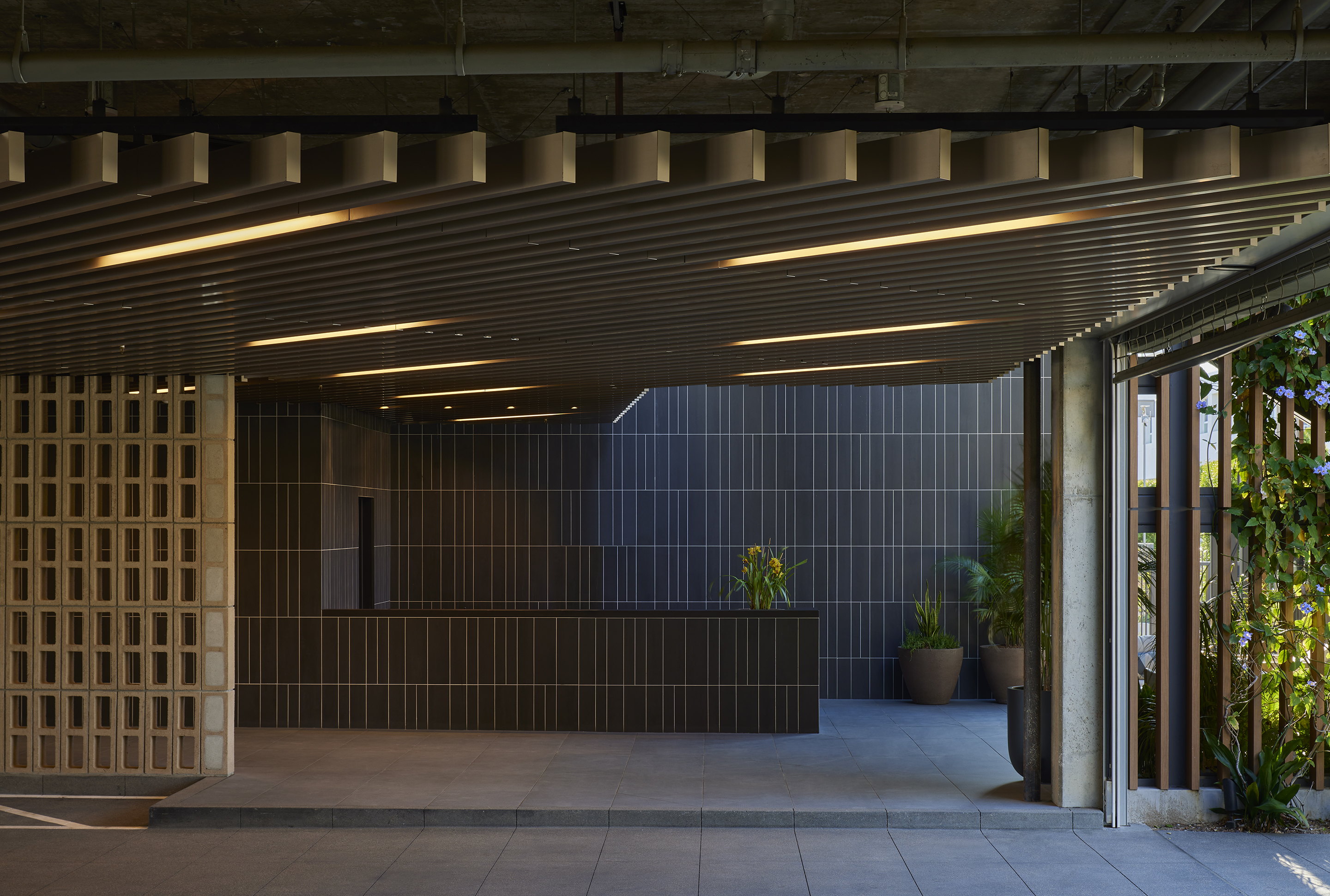 Lobby with dark tiled reception desk beneath a curved timber-slatted ceiling