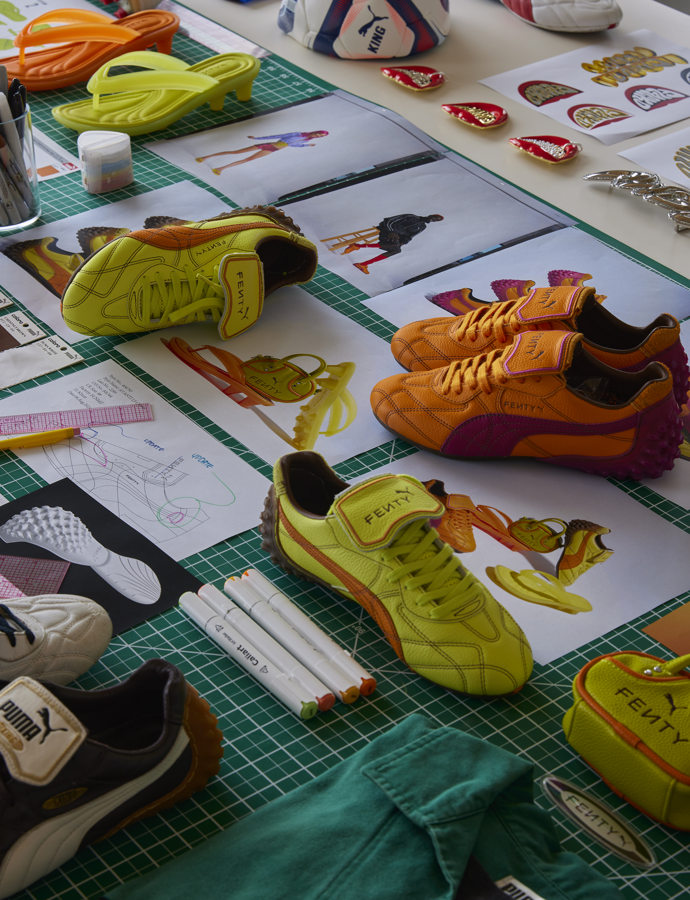 Prototype footwear, sketches and colour chips laid out on a cutting mat