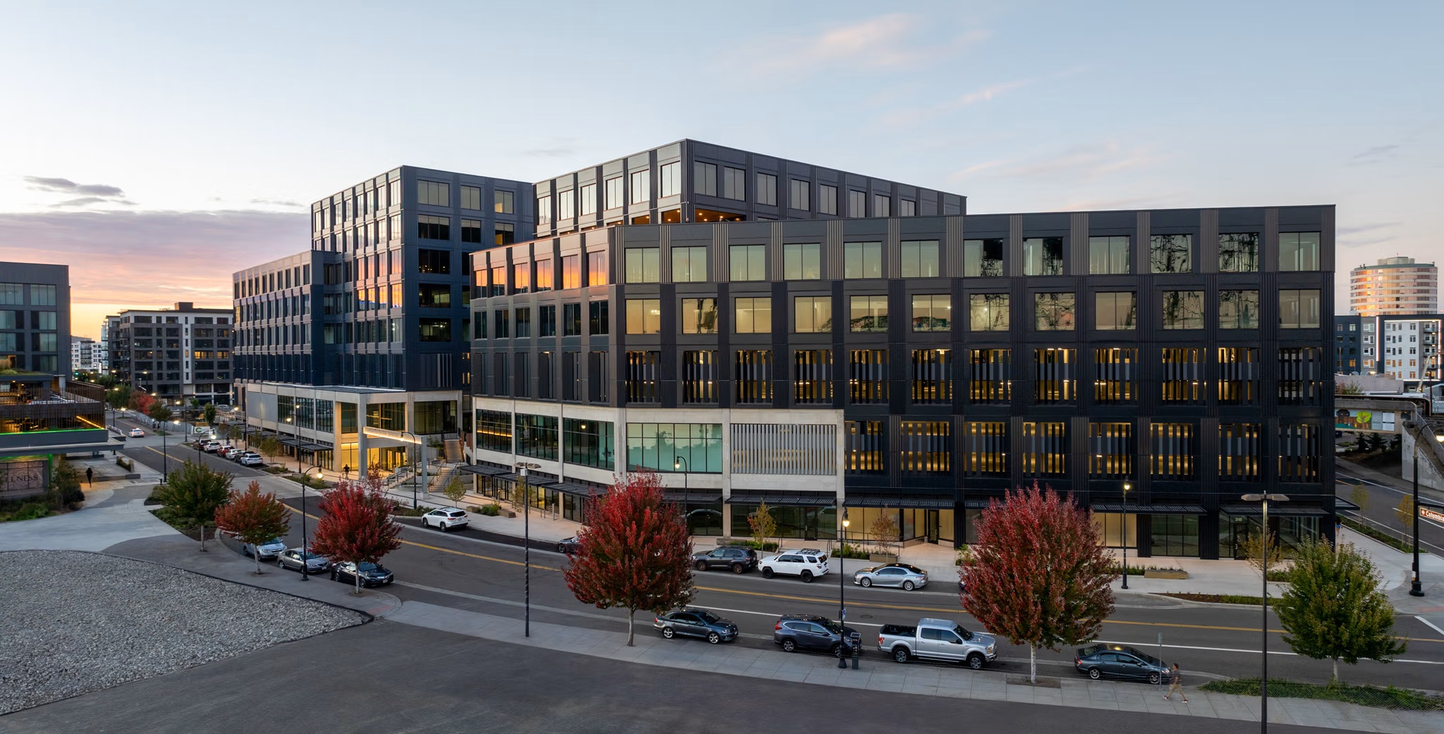 Street-corner view of Terminal 1 at dusk with lit interiors and autumn street trees