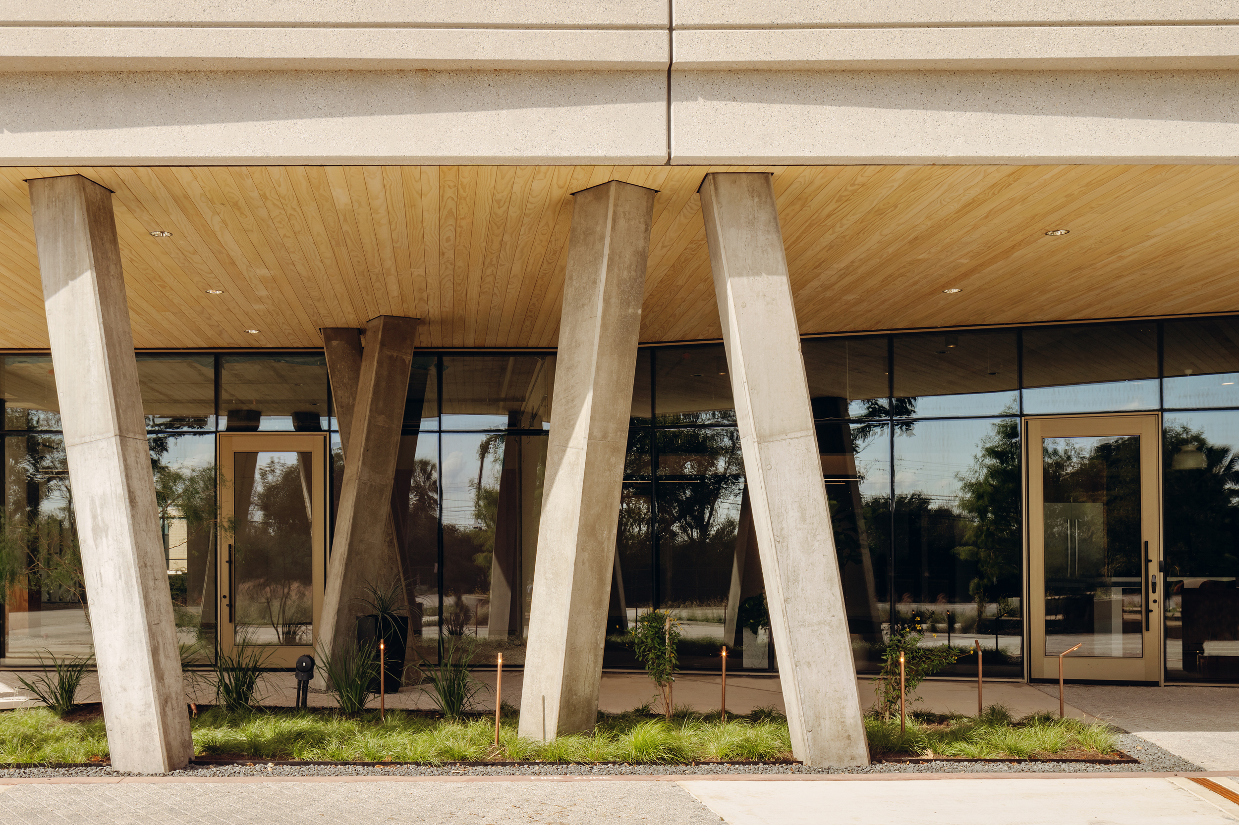 Broad elevation of splayed concrete columns beneath a timber soffit